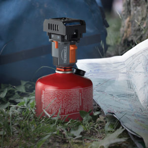 Camping Gaskocher neben Karte auf Gras liegend