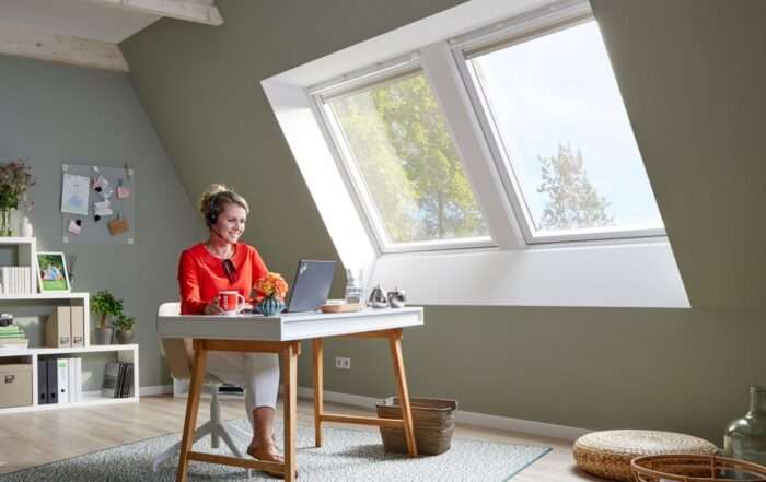 Frau arbeitet zu Hause an einem Laptop am Schreibtisch im Dachgeschoss